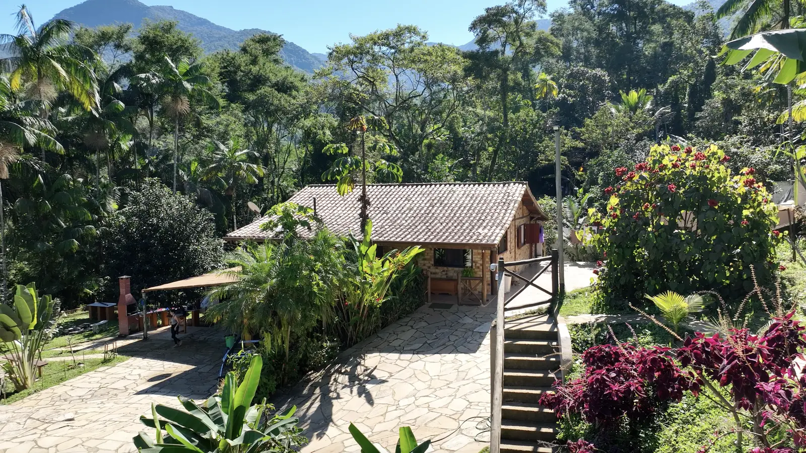 Casa Ipê cercada pelo jardim florido e pelas montanhas de Paraty