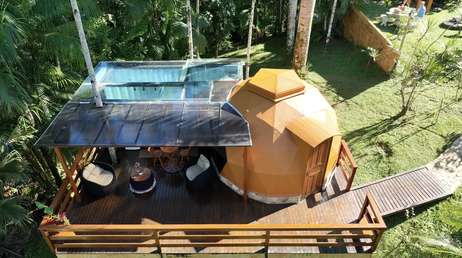 Vista aérea do Domo João de Barro, com deck de madeira, estar coberto e piscina de borda de vidro